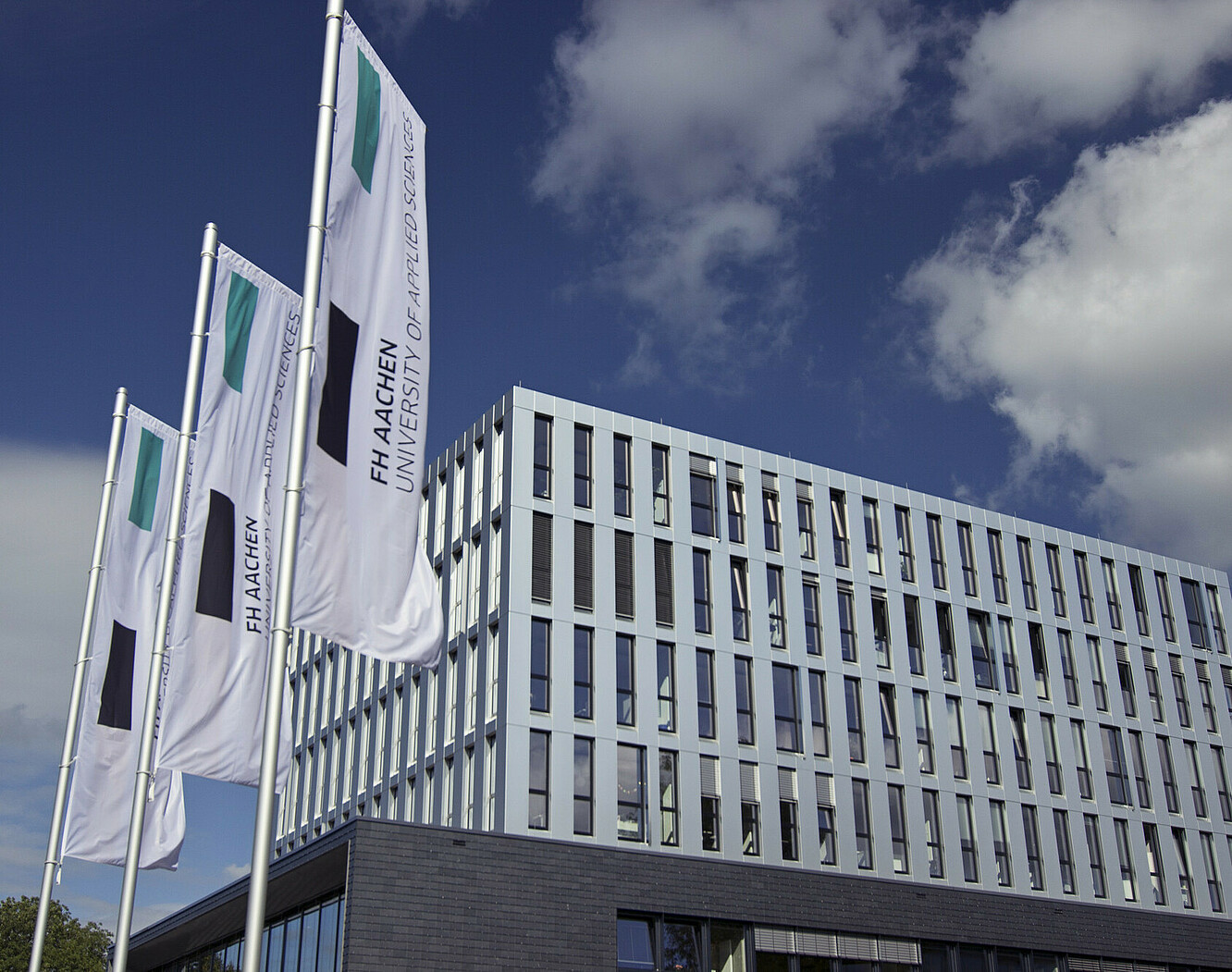 Das Hauptgebäude der FH Aachen mit 3 davor stehenden wehenden Fahnden.